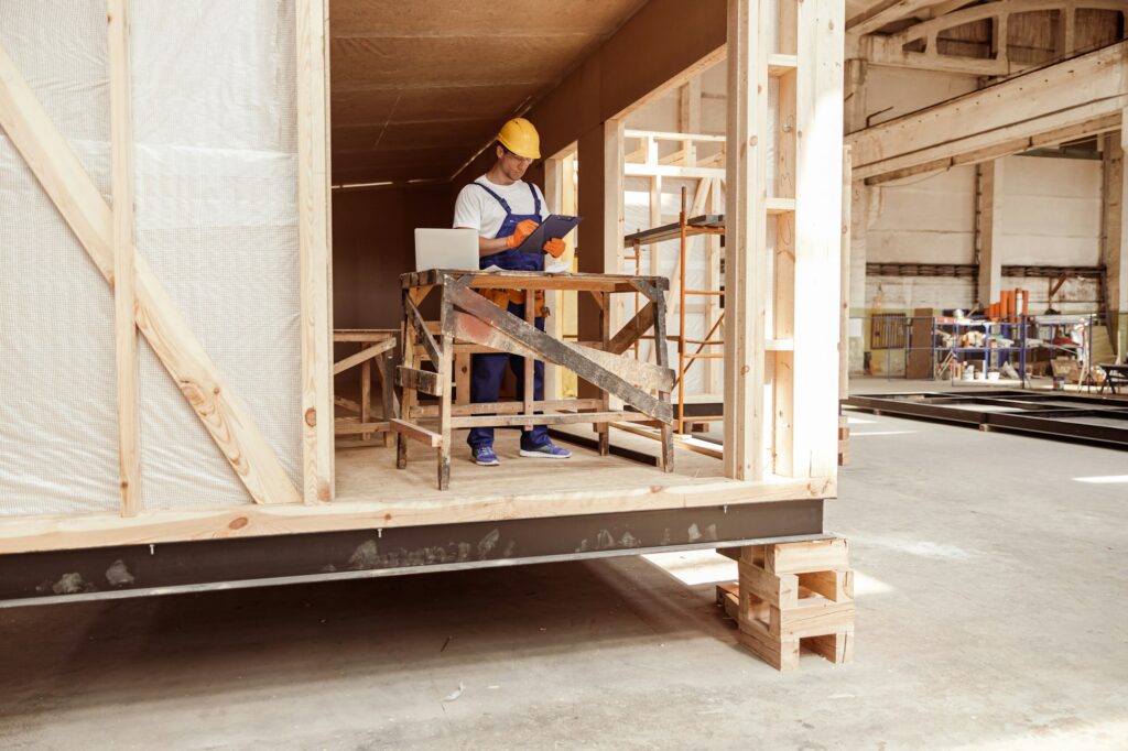 Male builder writing on clipboard at construction site